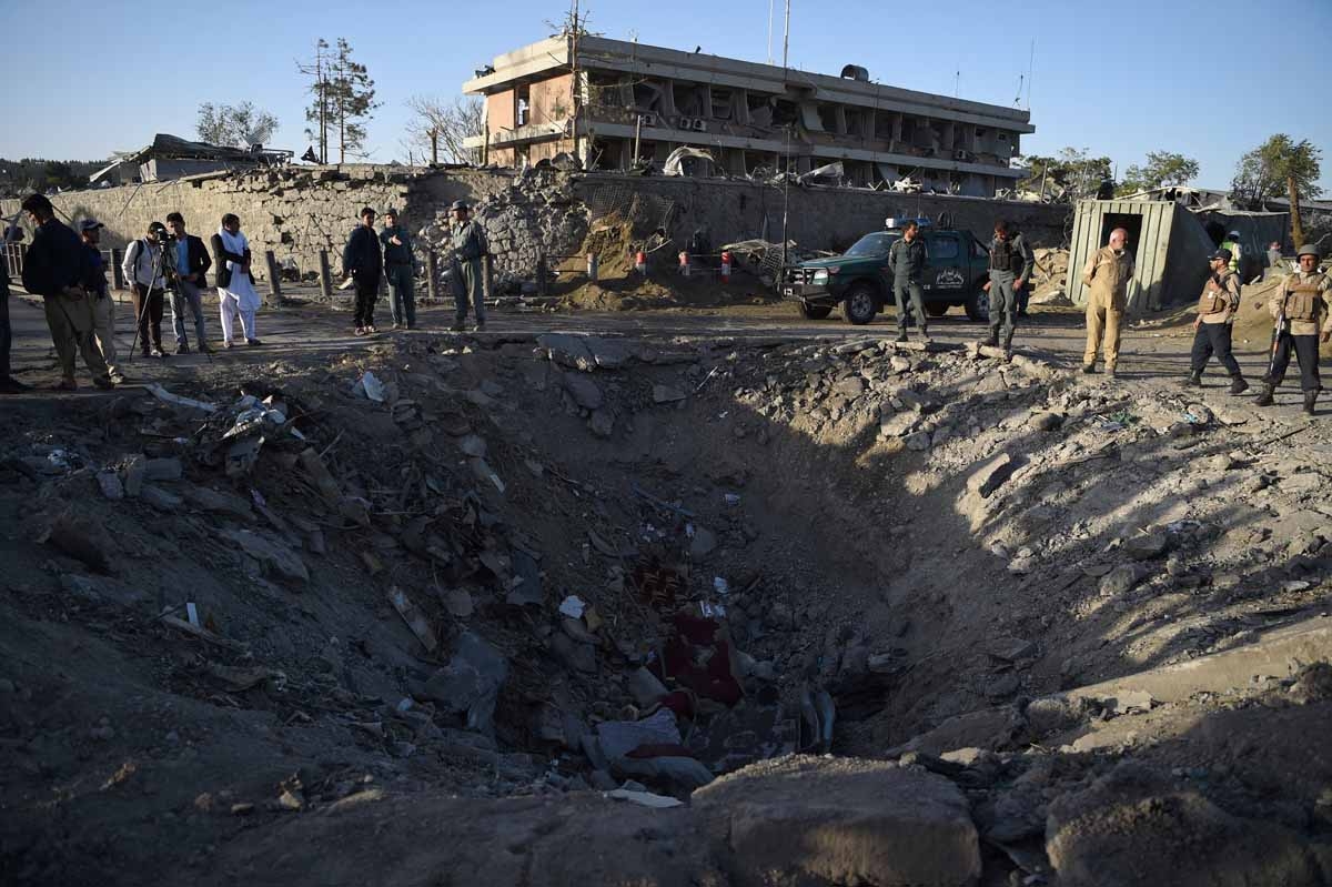 Afghan security forces and residents stand near the crater left by a truck bomb attack in Kabul on May 31, 2017.