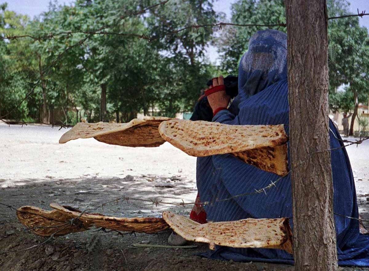 An Afghan woman sits by the bread she received from a UN subsidized backery in Kabul 13 June 2001