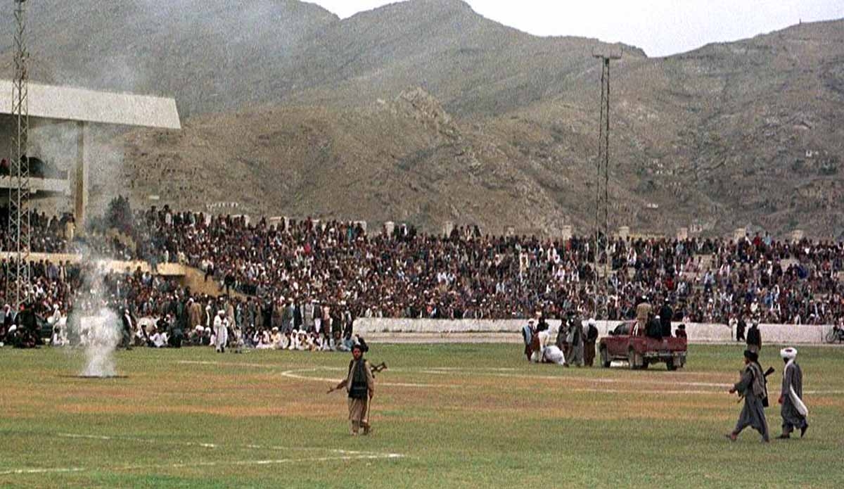 Taliban fighters and Kabul residents watch as surgeons cut off a thief's hand at the national stadium in Kabul, under Taliban rule. August, 1998.