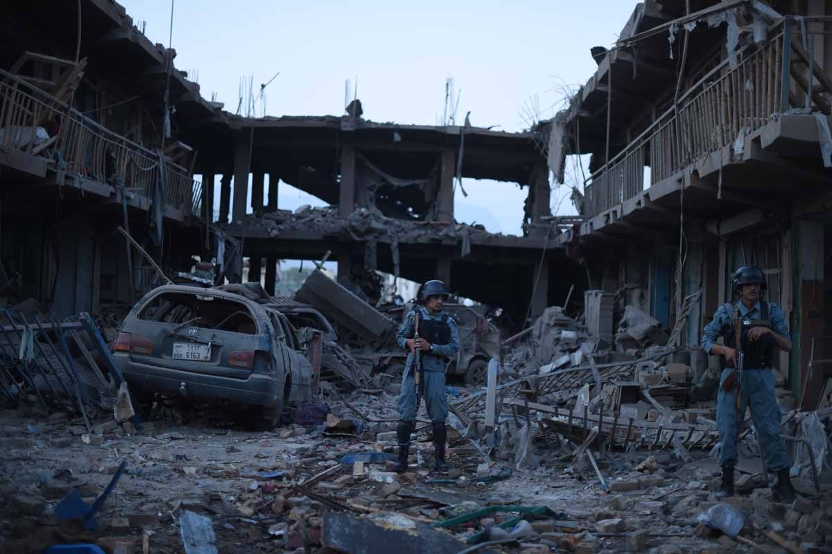 Afghan policemen stand guard at a market destroyed by a powerful truck bomb in Kabul on August 7, 2015.