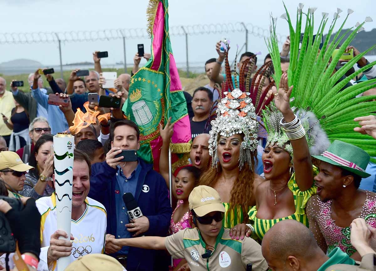 Mayor of Rio Eduardo Paes (L) carries the Olympic torch next to dancers from the Mangueira Samba School, ahead of the Rio 2016 Olympic Games in Rio de Janeiro on August 3, 2016 Mayor of Rio Eduardo Paes (L) carries the Olympic torch next to dancers from the Mangueira Samba School, ahead of the Rio 2016 Olympic Games in Rio de Janeiro on August 3, 2016