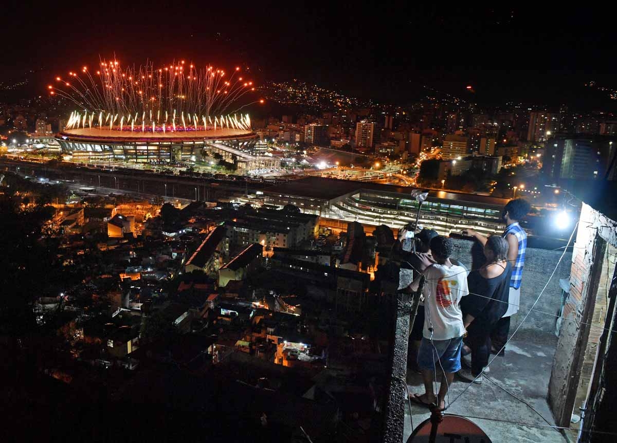 People watch fireworks exploding over the Maracana stadium, from a terrace in the favela Mangueira, during the opening ceremony of the Rio 2016 Olympic Games in Rio de Janeiro on August 5, 2016 People watch fireworks exploding over the Maracana stadium, from a terrace in the favela Mangueira, during the opening ceremony of the Rio 2016 Olympic Games in Rio de Janeiro on August 5, 2016