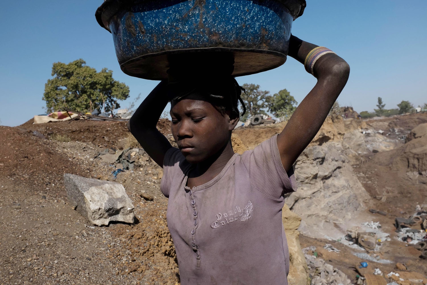 A young girl carries a bucket full of crushed stones at a quarry in Ouagadougou where adults and children work on December 17, 2015. A young girl carries a bucket full of crushed stones at a quarry in Ouagadougou where adults and children work on December 17, 2015.