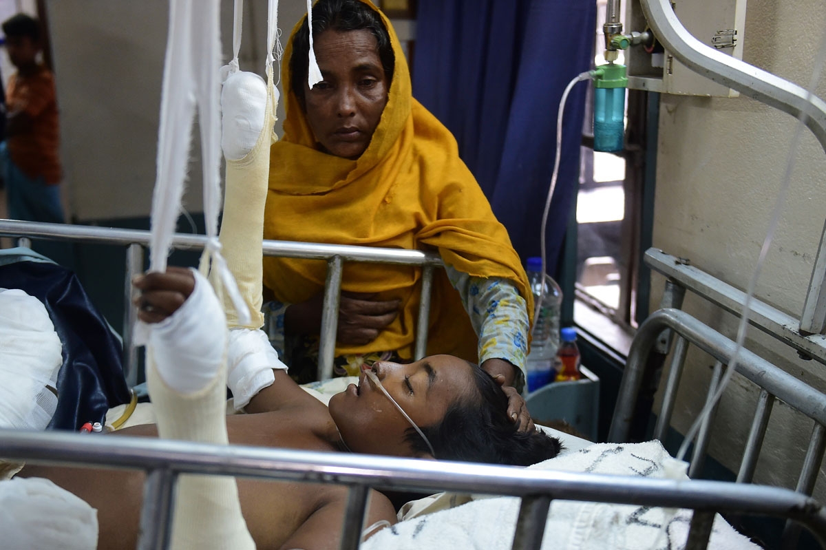 In this picture taken on September 13, 2017, Rohingya Muslim refugee Rashida Begum stands next to her son Azizul Hoque, 15, as he is treated after being injured by a landmine while crossing from Myanmar to Bangladesh, at a hospital in Cox's Bazar.