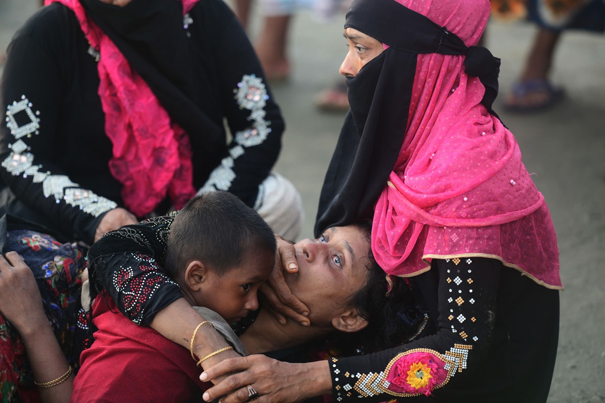 Relatives of a Rohingya refugee comfort her after crossing the border from Myanmar by boat, on the Bangladeshi shore of the Naf river in Teknaf on September 14, 2017.