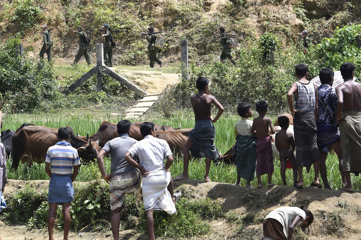 Rohingya Muslim refugees in Jalpatoli refugee camp in the no-man's land area between Myanmar and Bangladesh watch as Myanmar soldiers patrol on the other side of the border, near Gumdhum village in Ukhia on September 16, 2017.