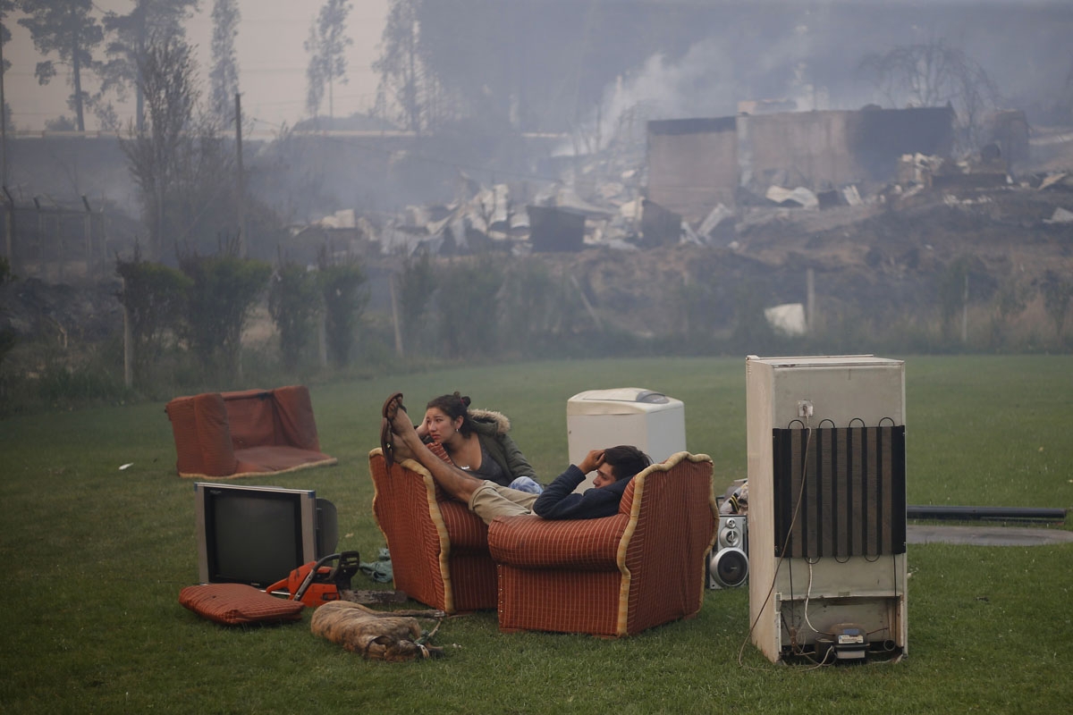 A young couple rest in a football field after a forest fire devastated Santa Olga, 240 kilometres south of Santiago, on January 26, 2017.