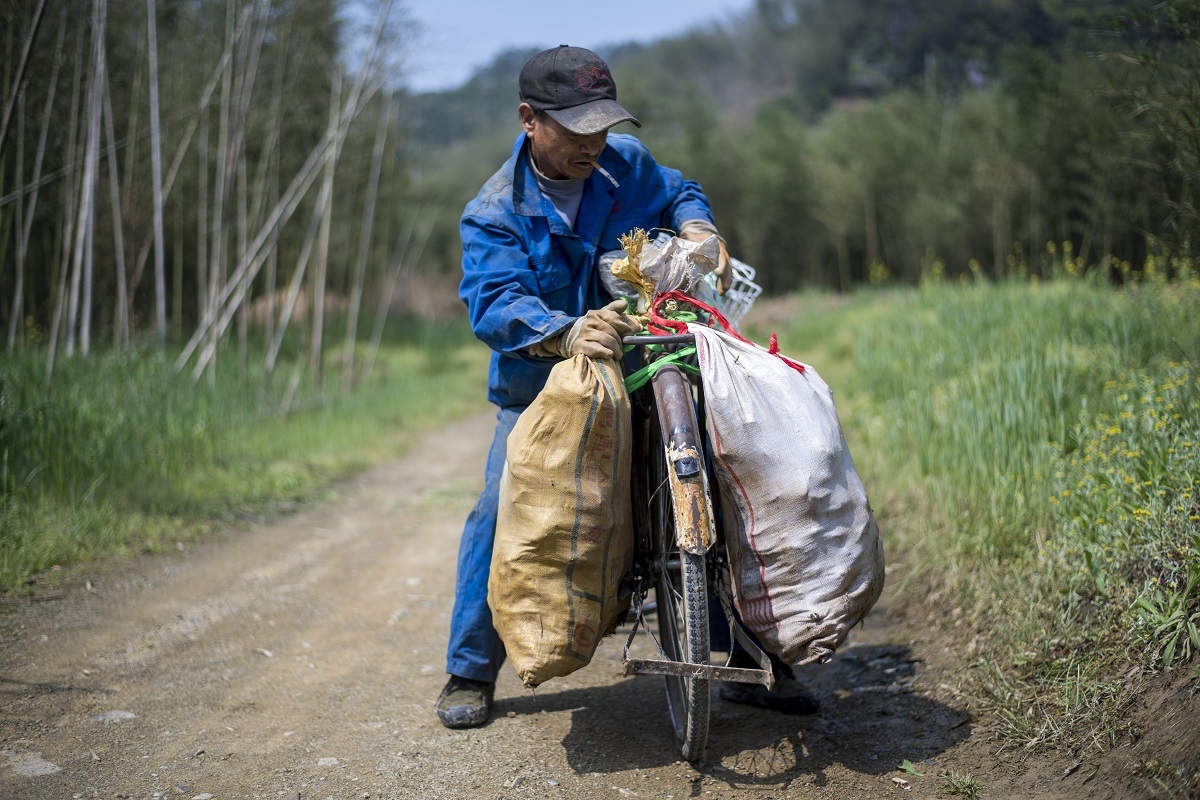 This picture taken on April 12, 2017 shows Xu Weifu attaching two bags of bamboo to his bicycle to transport it to the market in Taihuyuan near the city of Lin'an, Zhejiang Province.