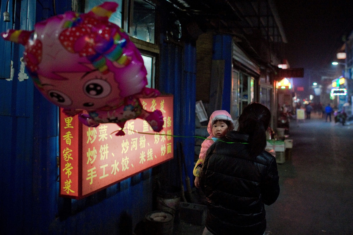 This picture taken on February 15, 2017 shows a woman carrying a girl in the Heiqiaocun migrant village in Beijing.