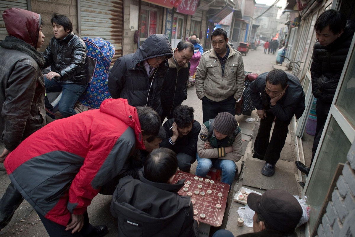 This picture taken on February 15, 2017 shows people playing Chinese chess in the Heiqiaocun migrant village in Beijing.
