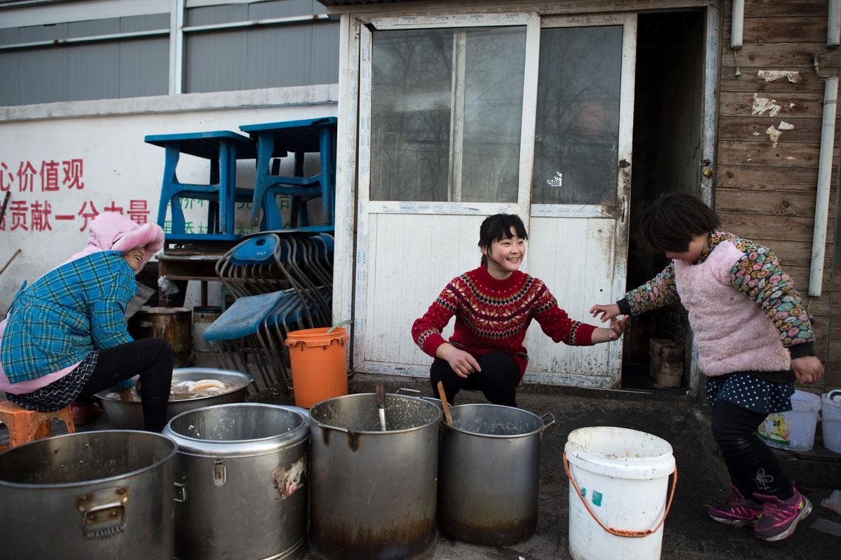 This picture taken on January 18, 2017 shows workers cleaning dishes outside a restaurant in the Heiqiaocun migrant village in Beijing.