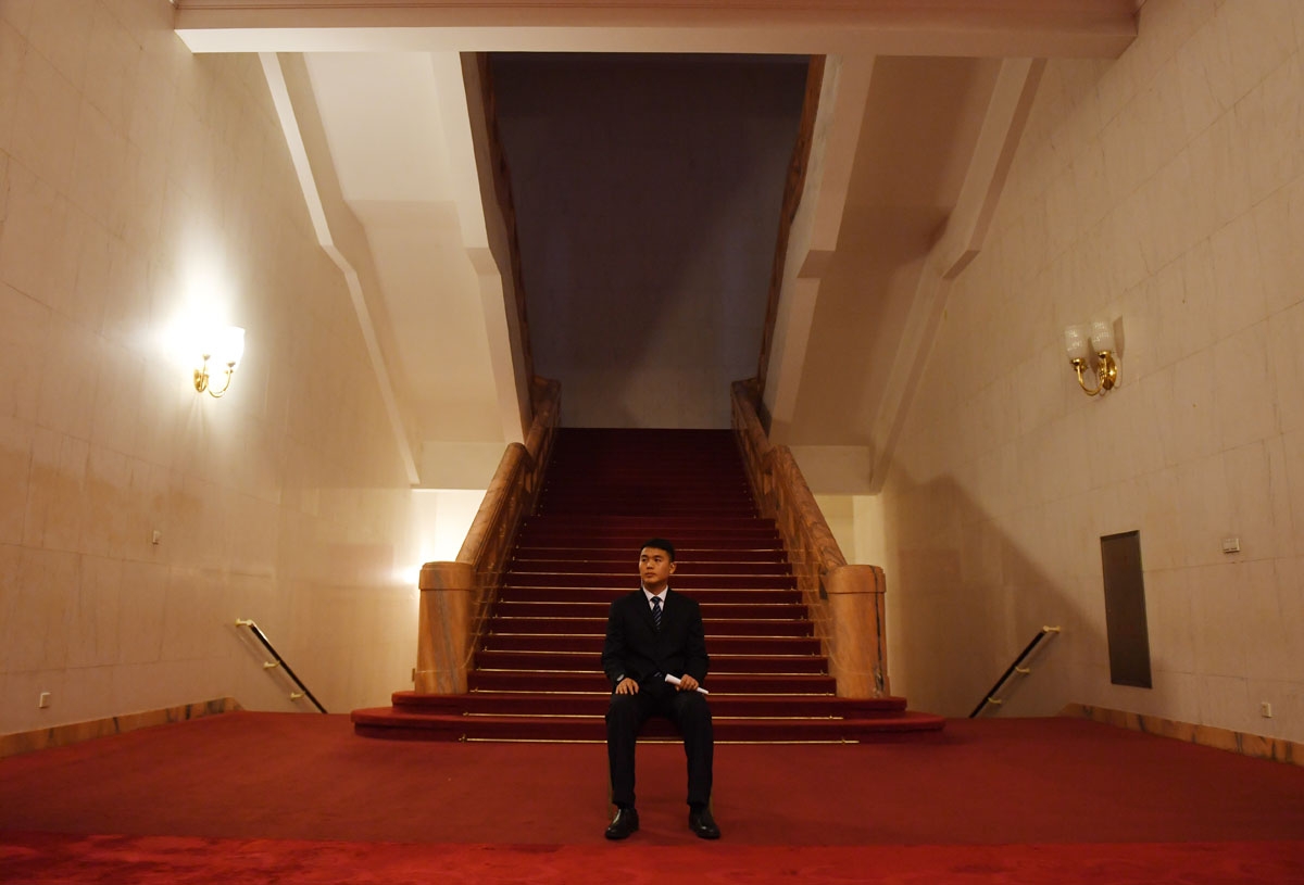 A security guard sits below a stairwell in the Great Hall of the People near the venue where Hong Kong delegates were meeting during the National People's Congress in Beijing on March 7, 2017.