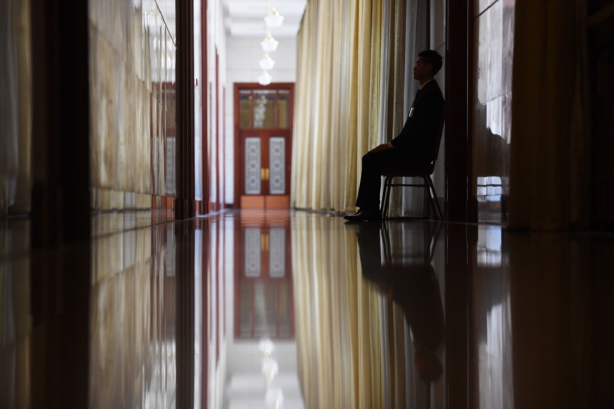 A security guard sits in a corridor leading to the Hong Kong Hall during the National People's Congress at the Great Hall of the People in Beijing on March 7, 2017.