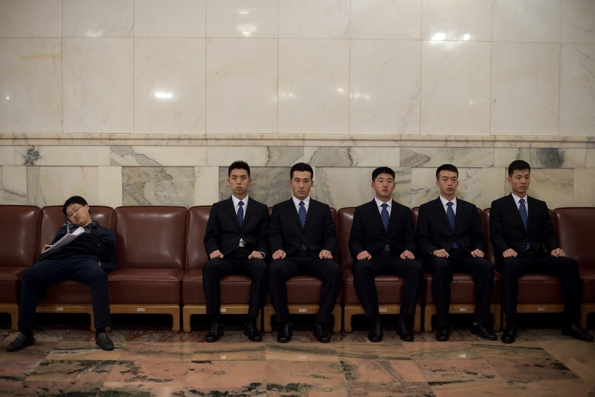 Security guards take a break as a man (L) sleeps during the second plenary session of the National People's Congress, China's legislature, at the Great Hall of the People in Beijing on March 8, 2017.
