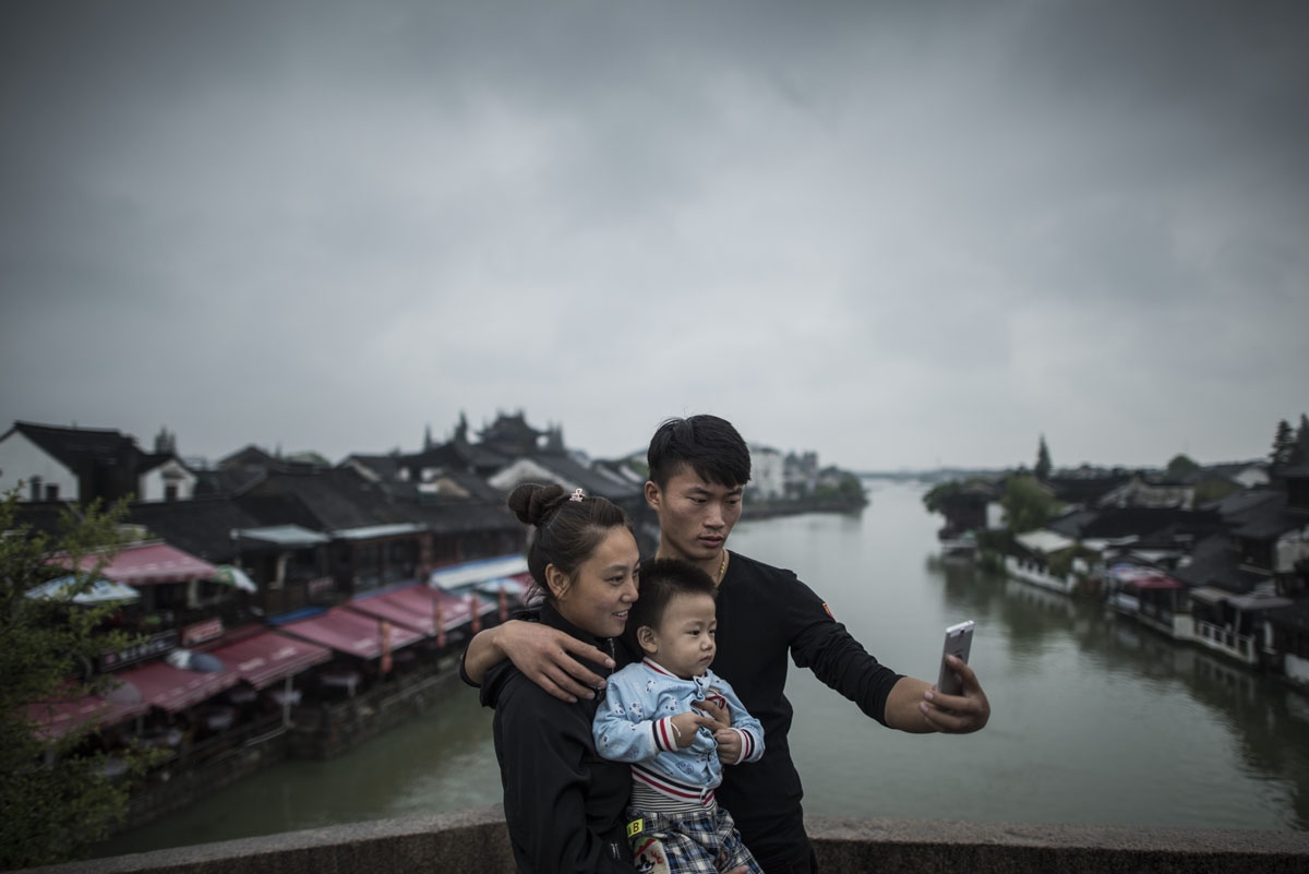 A man with his wife and his son pose for a picture in Zhujiajiao, on the outskirts of Shanghai, on September 7, 2016