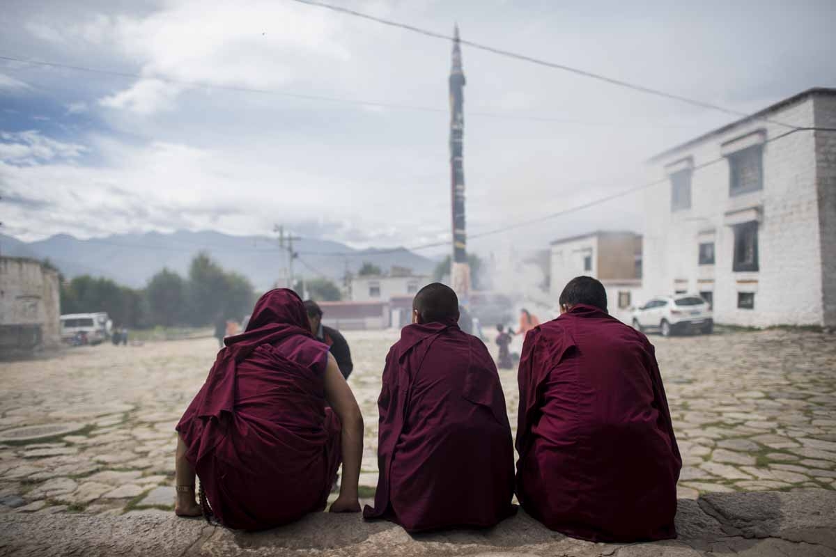 This picture taken on September 11, 2016 shows three young monks sitting in front of the Buddhist Sera monastery in the regional capital Lhasa, in China's Tibet Autonomous Region. 