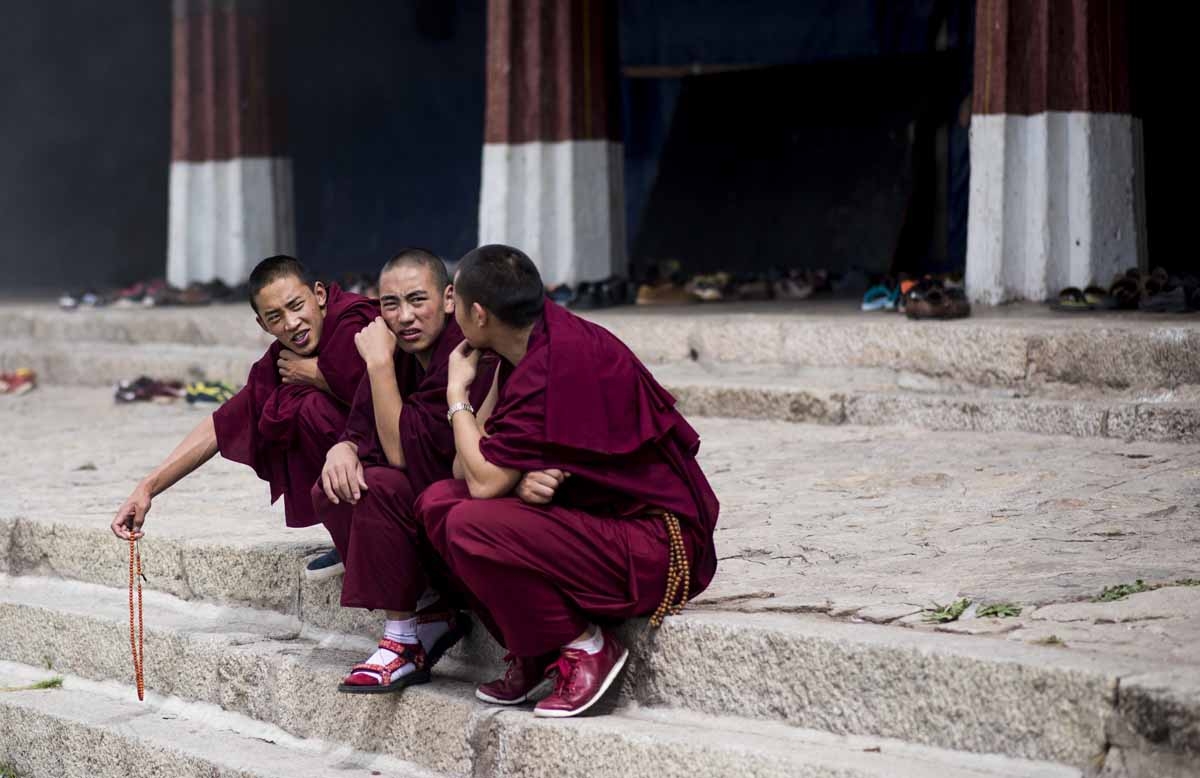 This picture taken on September 11, 2016 shows three young monks sitting in front of the Buddhist Sera monastery in the regional capital Lhasa, in China's Tibet Autonomous Region.