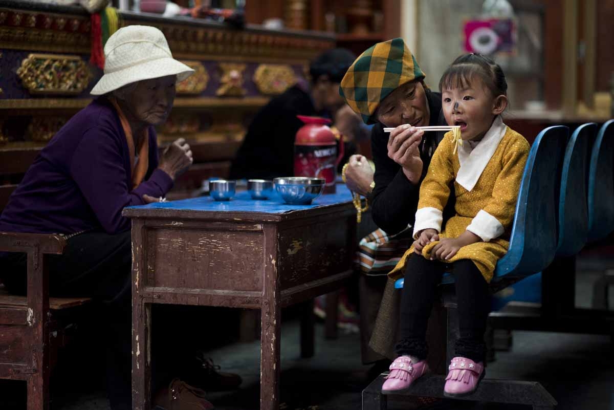 This picture taken on September 11, 2016 shows a girl and two woman having their lunch in a restaurant near the Buddhist Sera monastery in the regional capital Lhasa, in China's Tibet Autonomous Region. 