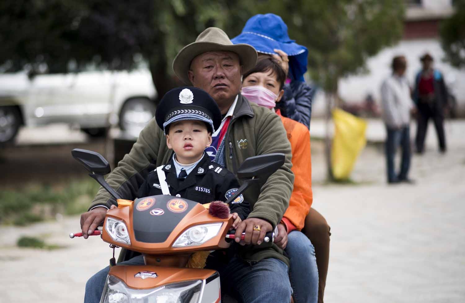 This picture taken on September 11, 2016 shows a man with his family on a scooter and his son dressed as a policeman as they exit the Buddhist Sera monastery in the regional capital Lhasa, in China's Tibet Autonomous Region.