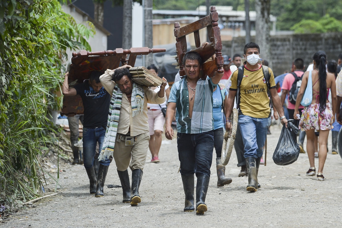 Locals walk carrying recovered belongings following mudslides caused by heavy rains in Mocoa, Putumayo department, southern Colombia on April 2, 2017.