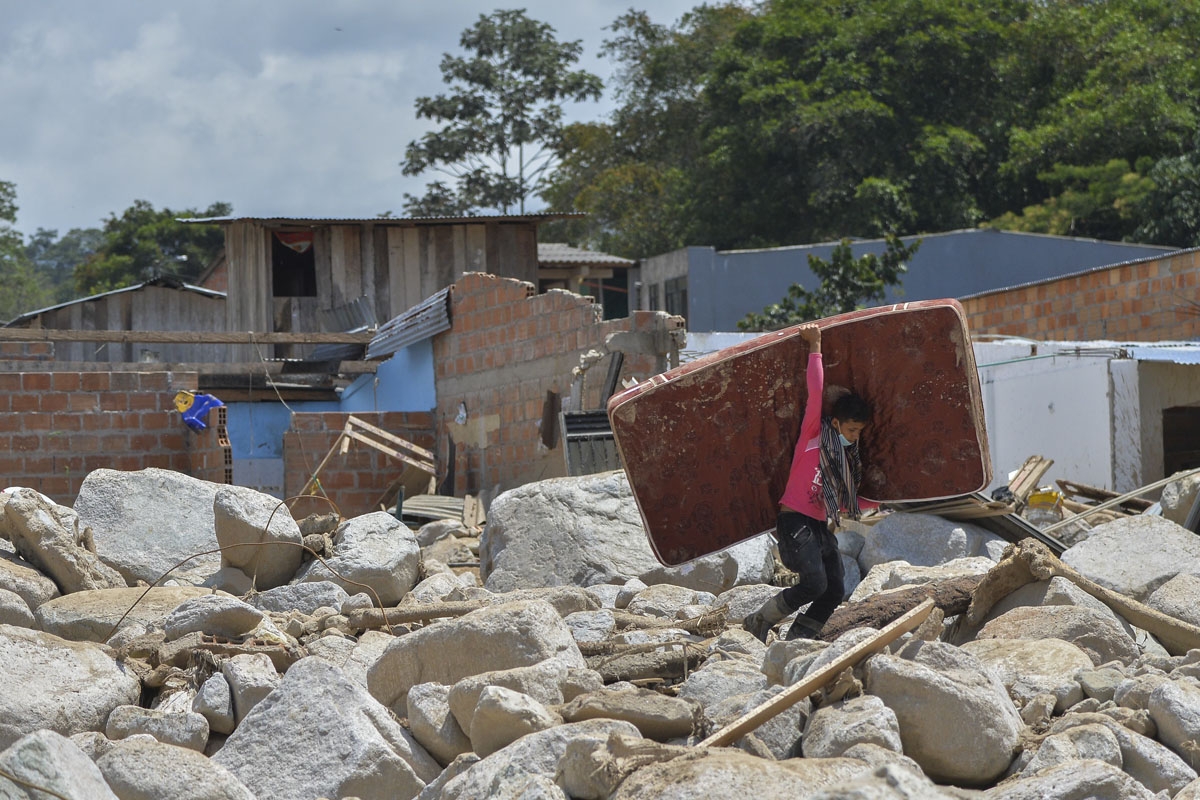 A young man carries a mattress amid the rubble left by mudslides caused by heavy rains in Mocoa, Putumayo department, southern Colombia on April 4, 2017.