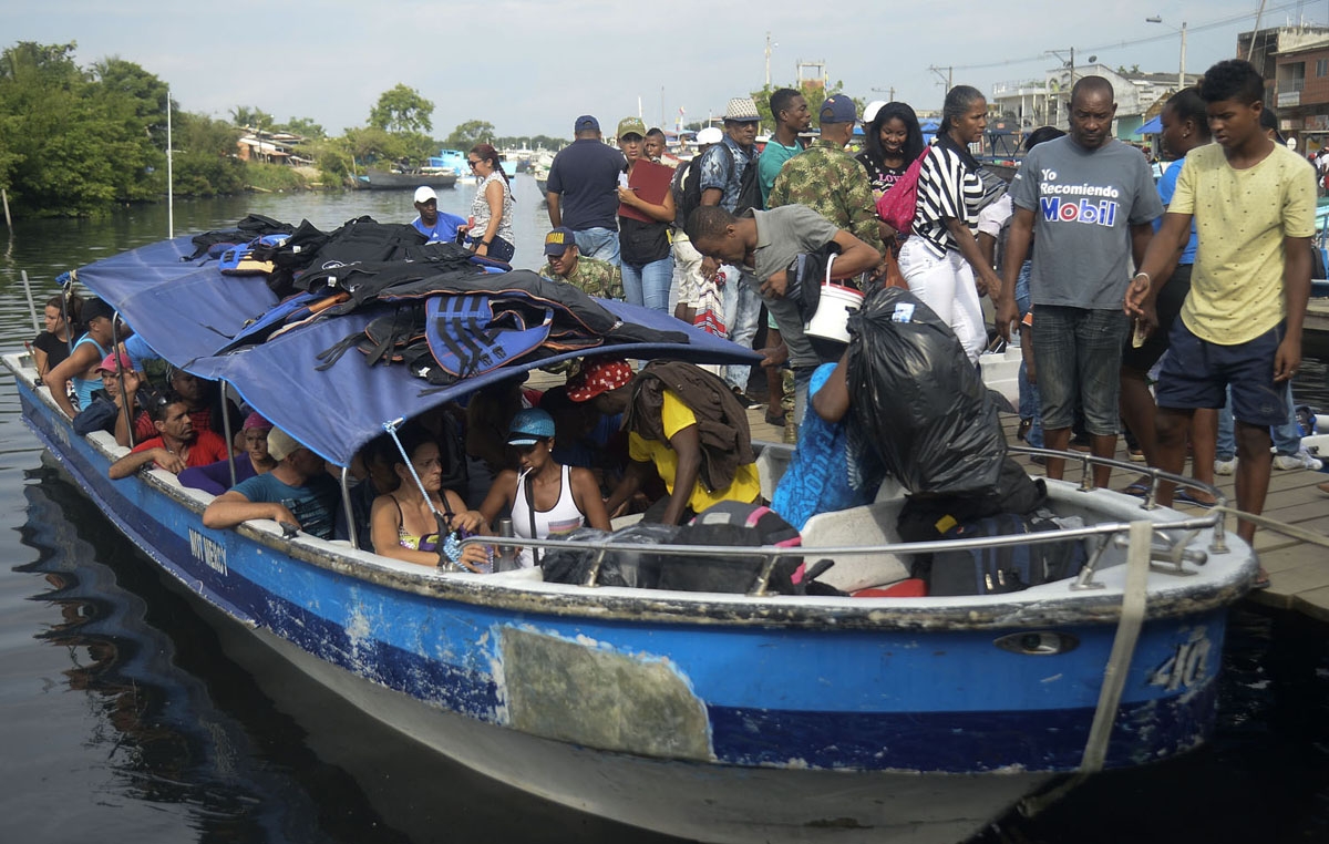 Cuban and Haitian migrants board a vessel to Capurgana, in the Caribbean Gulf of Uraba in northwestern Colombia, to illegally cross to Panama through the jungle, on August 6, 2016