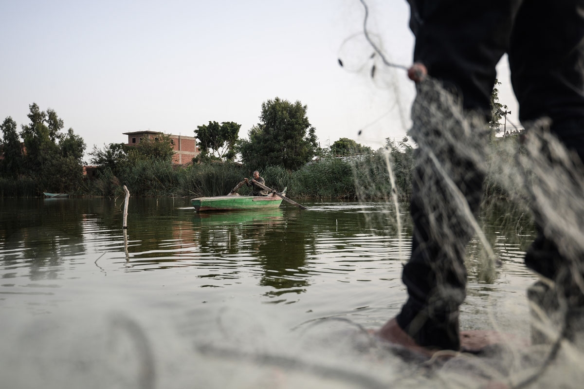 An Egyptian Fisherman handles a net on his boat in the waters of the Pharaonic Sea in the village of Kafr Fisha, province of Munuf, on June 16, 2018.