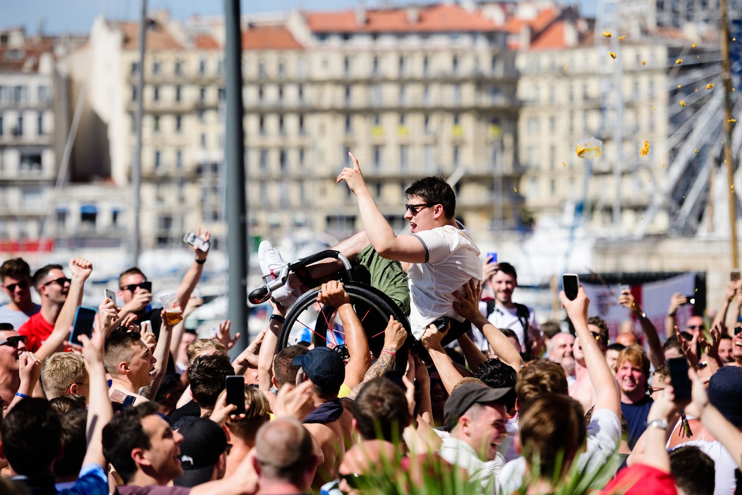 A man in a wheelchair is lifted into the air by England fans as they gather in Marseille, southern France, on June 10, 2016