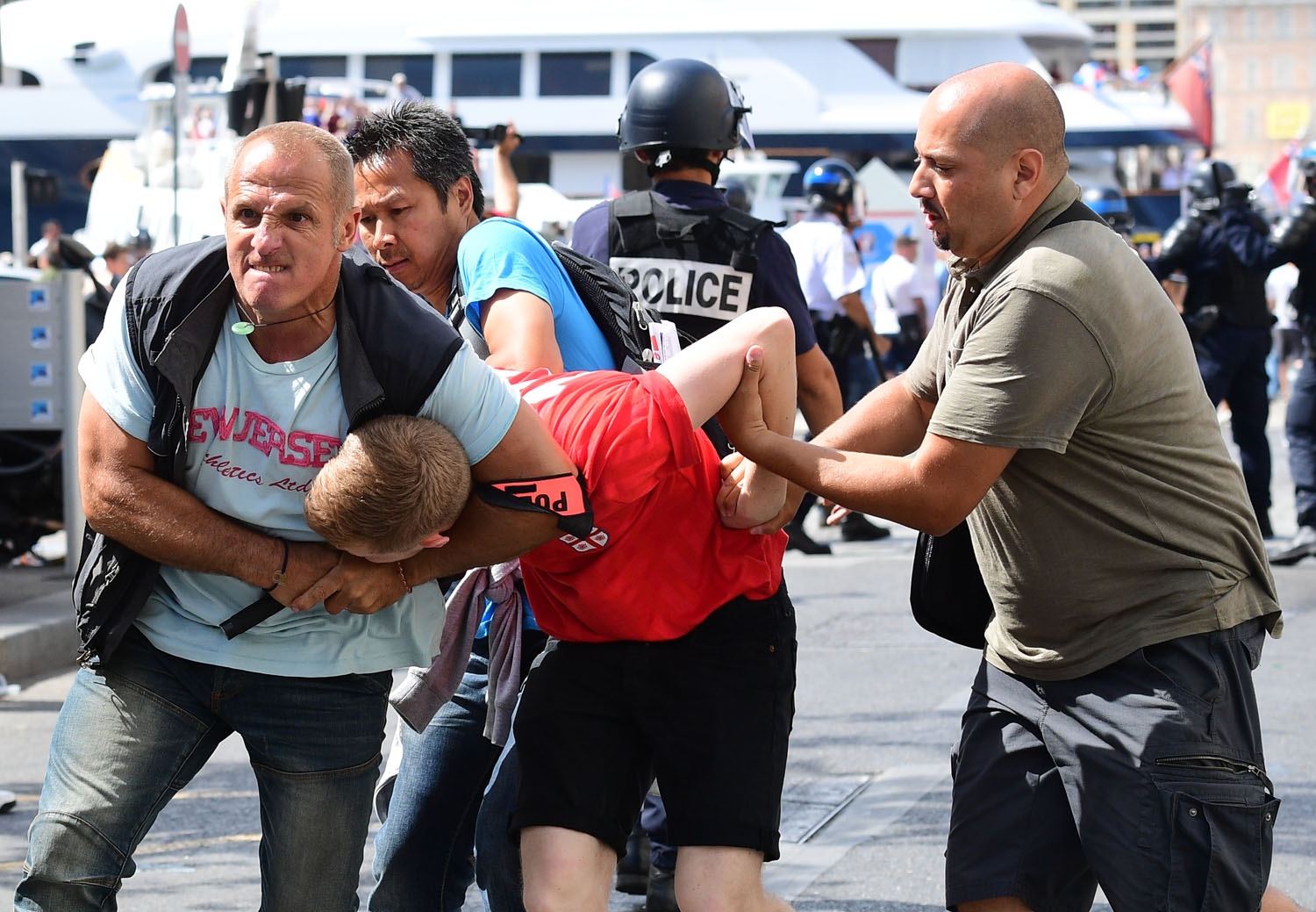 An England fan (C) is detained by police personnel following clashes between England fans and police in the city of Marseille, southern France, on June 11, 2016