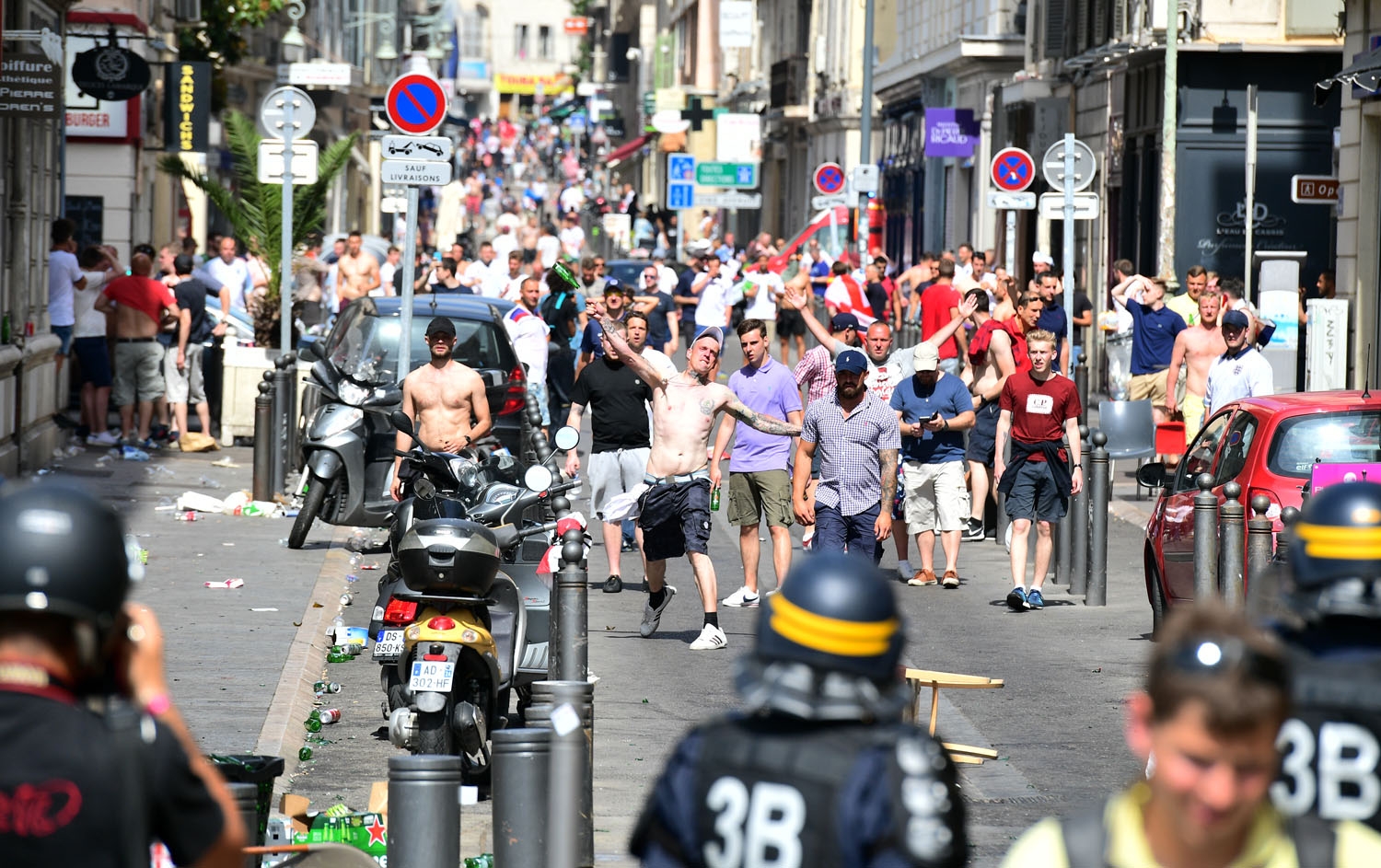 An England fan (C) throws a bottle towards police personnel as England fans gather in the city of Marseille, southern France, on June 11, 2016, ahead of the Euro 2016 football match between England and Russia