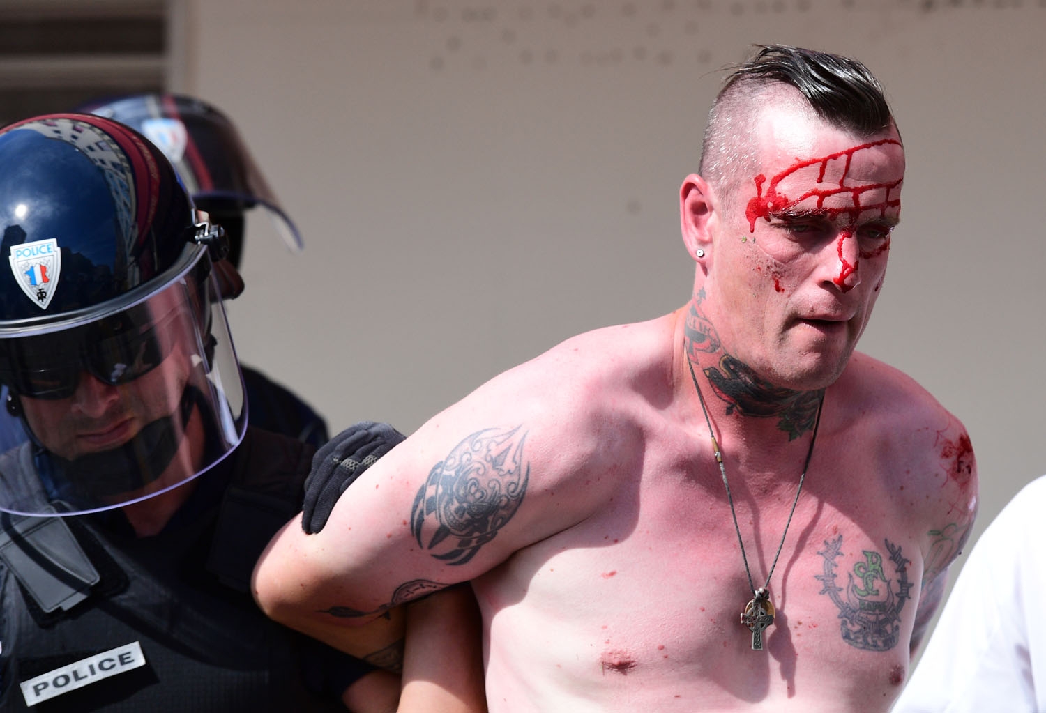 An injured England fan is detained by police personnel as England fans gather in the city of Marseille, southern France, on June 11, 2016