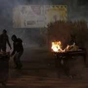 People stand behind a burning wheelie bin during a protest in Bobigny, a district of northeast Paris, to denounce police brutality after a black man was allegedly sodomised with a baton during an arrest while in their custody in Paris on February 11, 2017