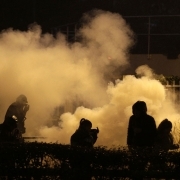 People stand as tear gas rises in Bobigny, northern Paris, on February 16, 2017 during a demonstration to demand justice for Theo, a 22-year-old youth worker who required surgery after his arrest last week in the gritty suburb of Aulnay-sous-Bois.