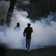 People stand as tear gas rises in Bobigny, northern Paris, on February 16, 2017 during a demonstration to demand justice for Theo, a 22-year-old youth worker who required surgery after his arrest last week in the gritty suburb of Aulnay-sous-Bois.