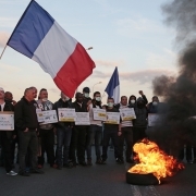 Protesters holding placards and a French flag stand behind a burning tyre outside the Fleury-Merogis prison, near Paris, on April 10, 2017, during a demonstration by prison guards after six of their colleagues were injured by inmates.