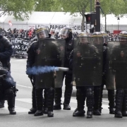 A French CRS anti-riot police officer fires a tear gas canister towards protesters during a march for the annual May Day workers' rally in Paris on May 1, 2017. / AFP PHOTO / Zakaria ABDELKAFI