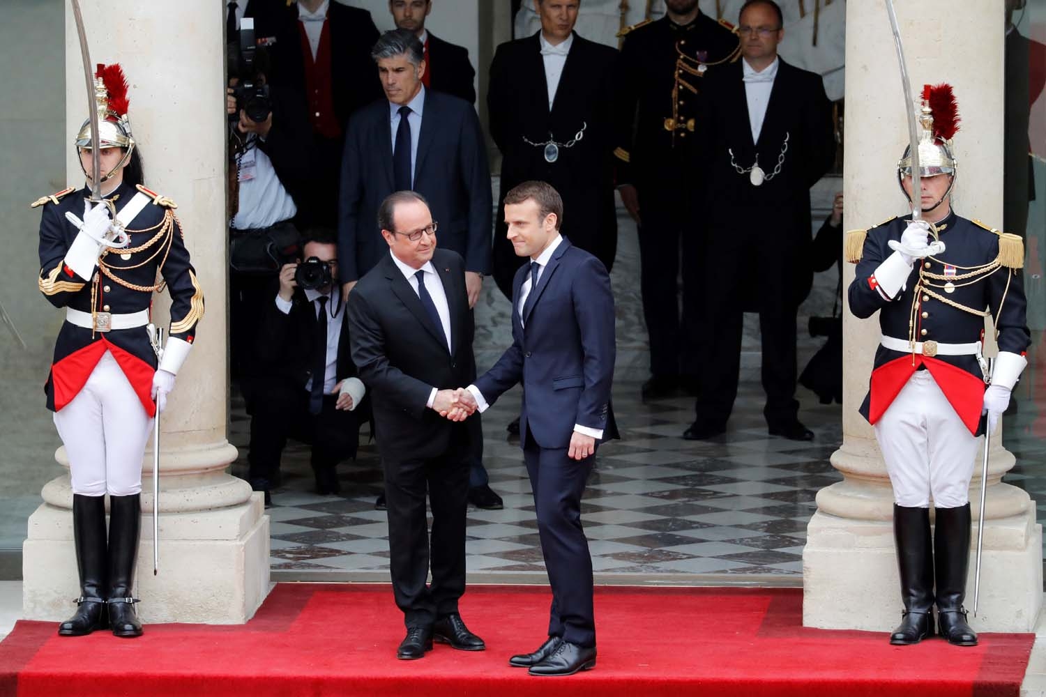 French newly elected President Emmanuel Macron (R) is welcomed by his predecessor Francois Hollande as he arrives at the Elysee presidential Palace for the handover and inauguration ceremonies on May 14, 2017 in Paris. / AFP PHOTO / POOL / Patrick KOVARIK
