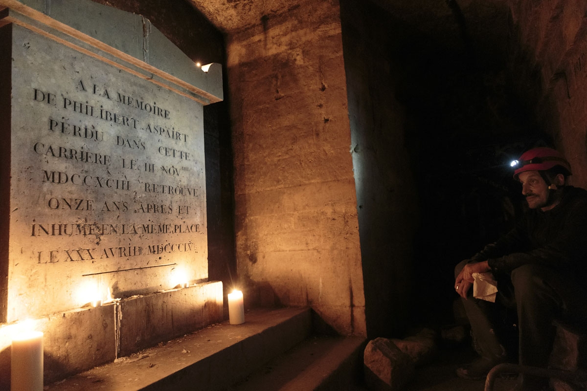 This photograph taken on November 7, 2017, shows Pascal, 36 as he pays his respects to the patron saint of cataphiles, Philibert Aspairt besides his grave in the banned catacombs of Paris.