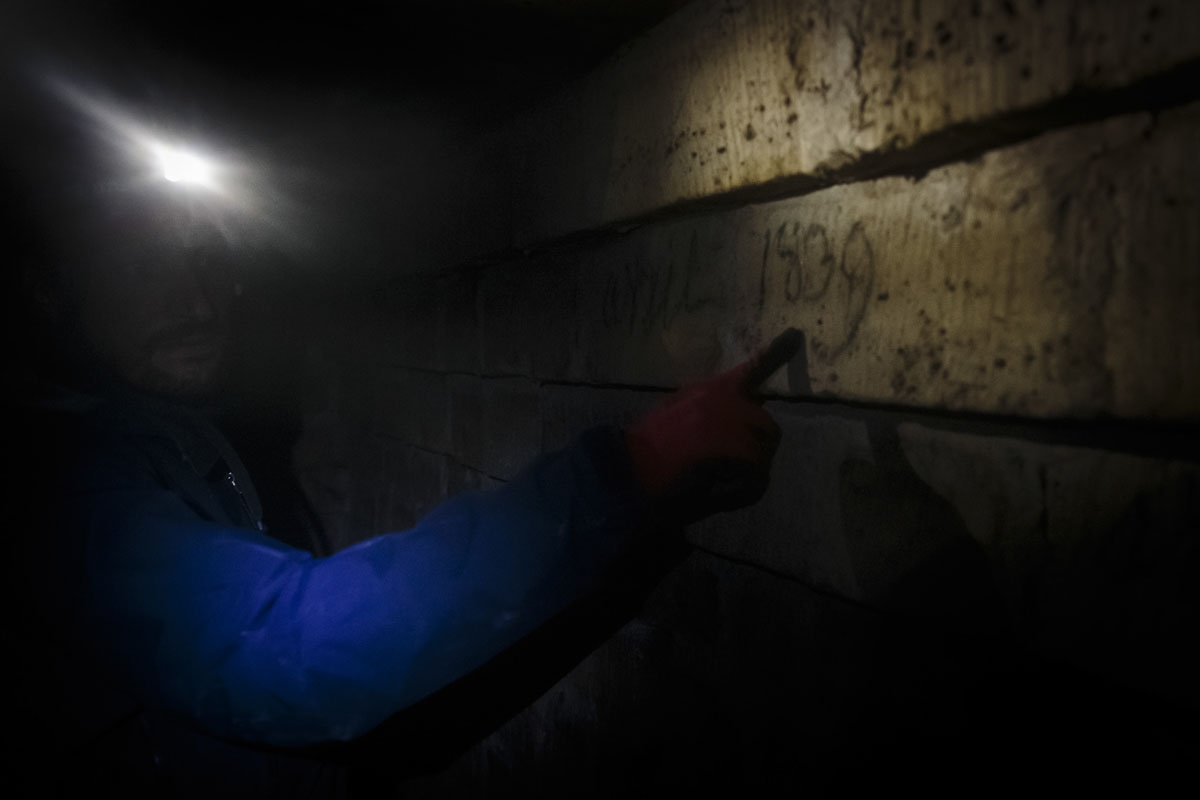 In this photograph taken on October 31, 2017, Pascal, 36, indicates a date on a wall in the banned catacombs of Paris.