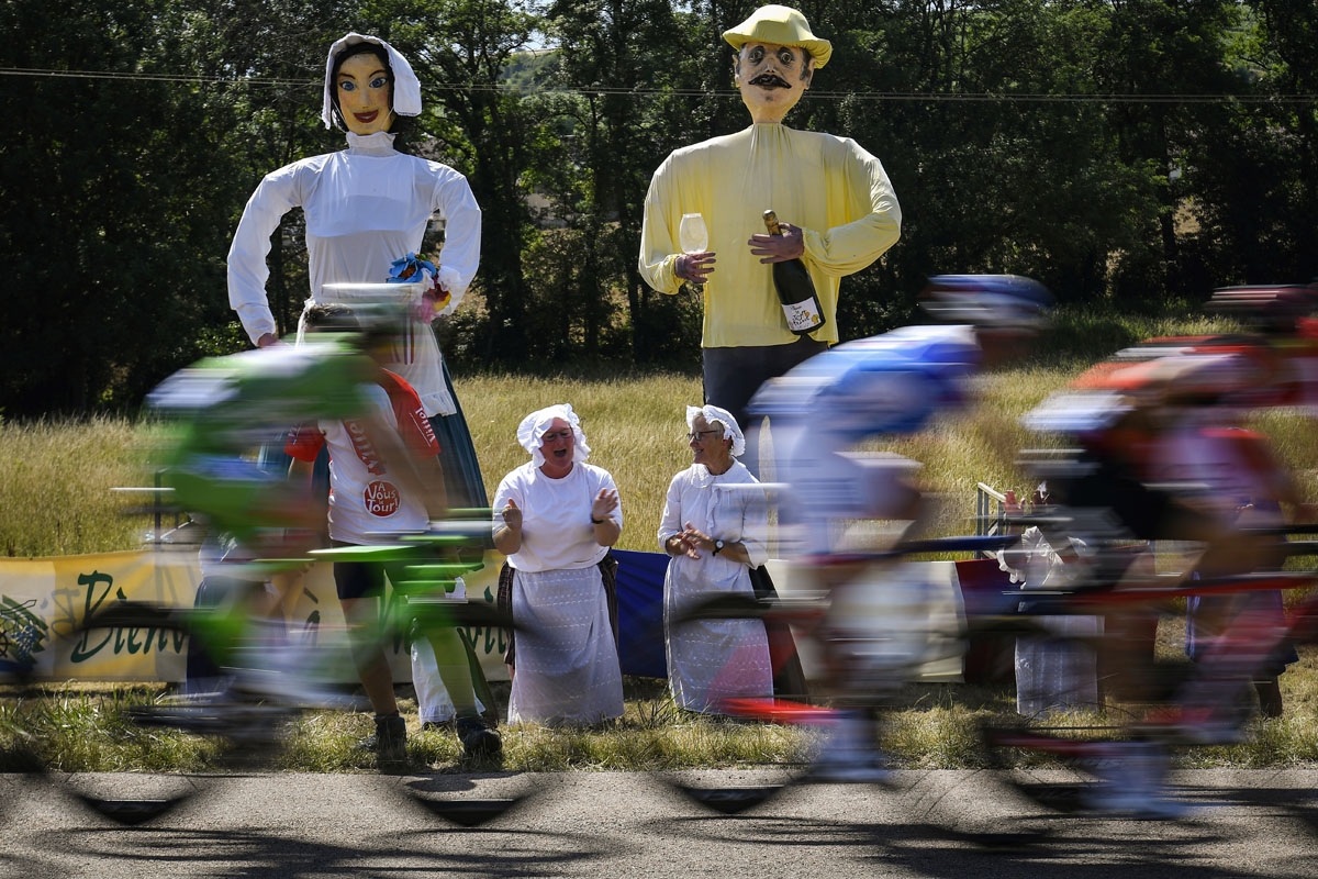 . Giants statues are pictured along the road as woman cheer during the 216 km sixth stage of the 104th edition of the Tour de France cycling race on July 6, 2017 between Vesoul and Troyes