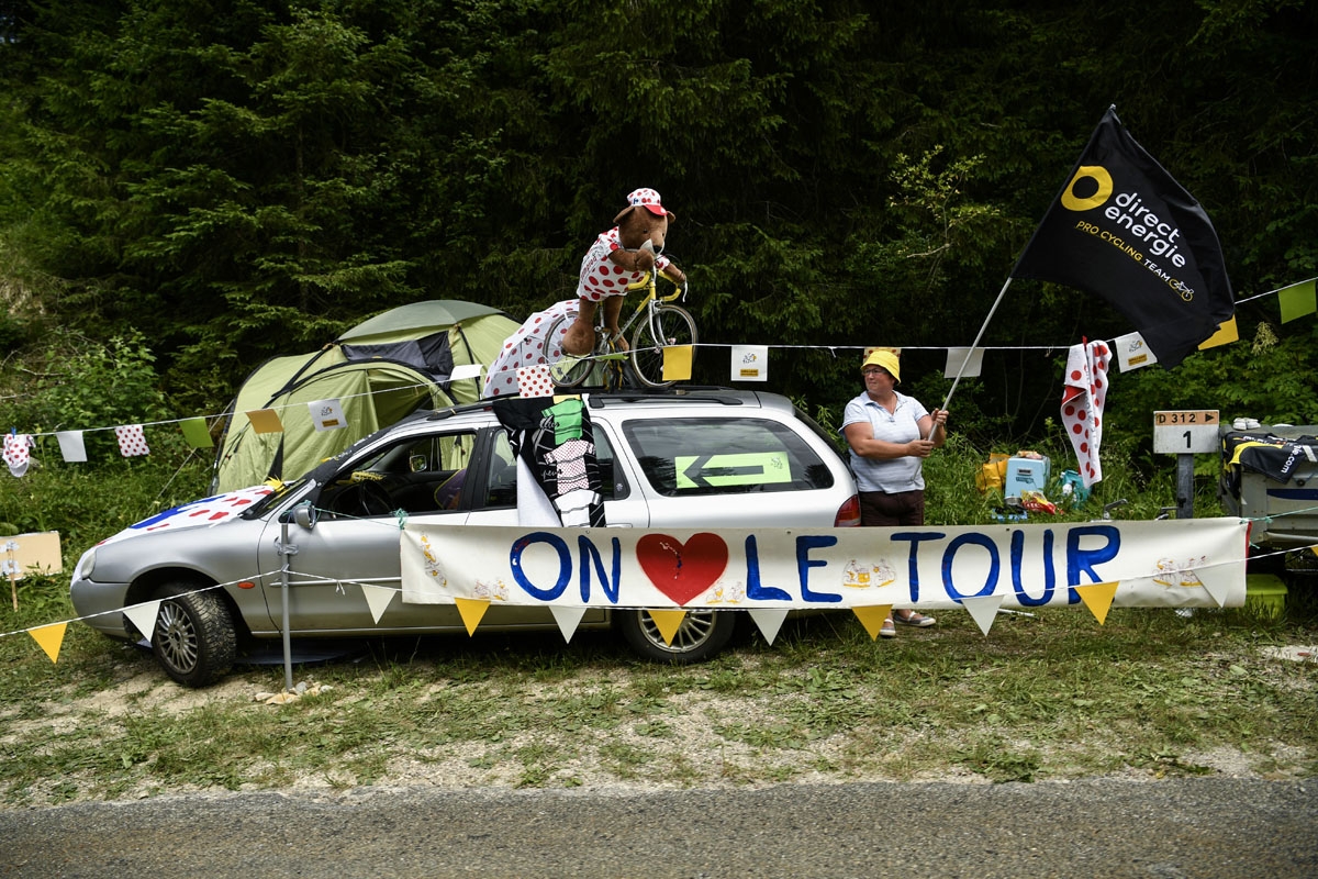 A supporter waves a flag of the France's Direct Energie cycling team behind a banner reading We love the Tour de France during the 187,5 km eighth stage of the 104th edition of the Tour de France cycling race on July 8, 2017 between Dole and Station des R