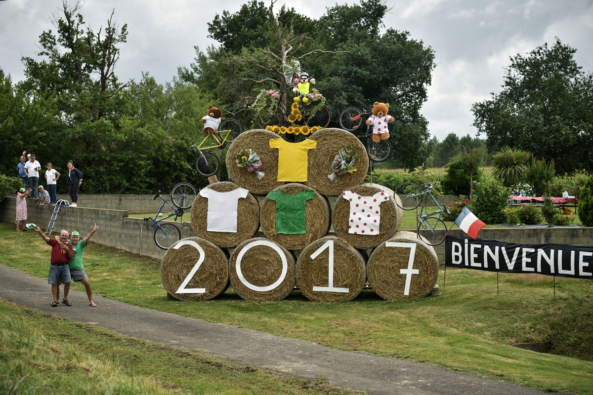 Supporters cheer along the road next to a placard reading Welcome (R) during the 203,5km eleventh stage of the 104th edition of the Tour de France cycling race on July 12, 2017 between Eymet and Pau