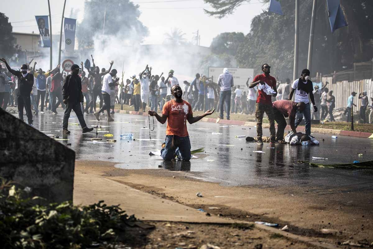 A supporter of Gabonese opposition leader Jean Ping prays in front of security forces blocking a demonstration trying to reach the electoral commission in Libreville on August 31, 2016 as another protestor lays on the ground in distress. A supporter of Gabonese opposition leader Jean Ping prays in front of security forces blocking a demonstration trying to reach the electoral commission in Libreville on August 31, 2016 as another protestor lays on the ground in distress.