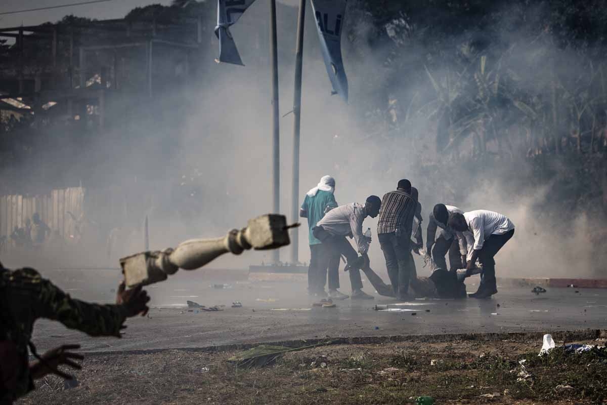 Supporters of Gabonese opposition leader Jean Ping try to evacuate a distressed comrade as they protest in front of security forces (unseen) blocking the demonstration which trying to reach the electoral commission in Libreville on August 31, 2016. Supporters of Gabonese opposition leader Jean Ping try to evacuate a distressed comrade as they protest in front of security forces (unseen) blocking the demonstration which trying to reach the electoral commission in Libreville on August 31, 2016.