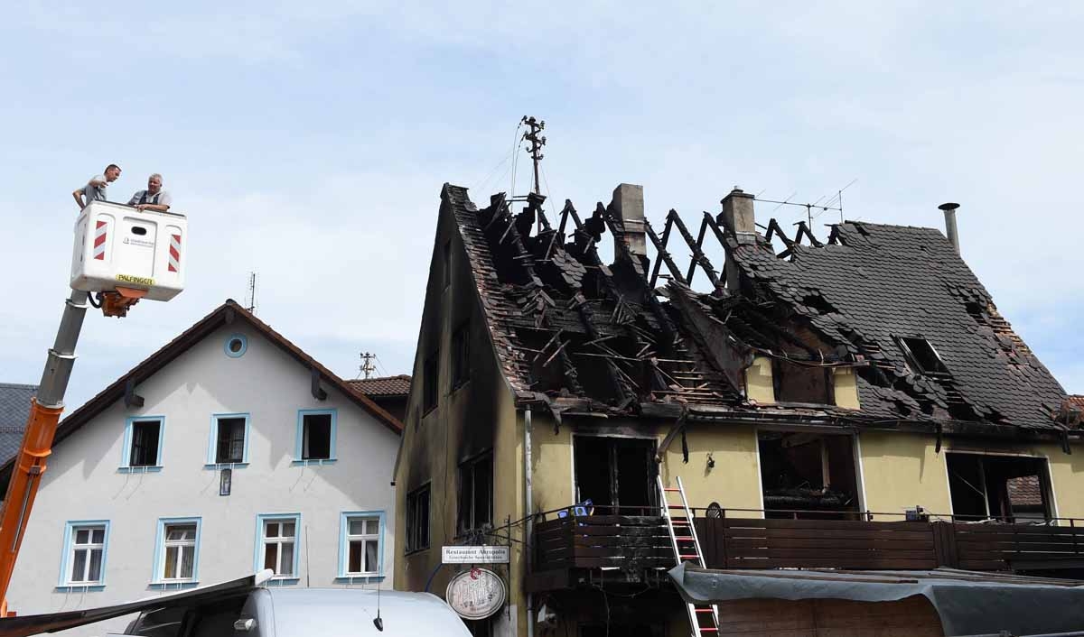 Two men stand on a lifting platform next to a burnt out shelter for asylum seekers in Goessweinstein, Bavaria, on August 20, 2016. Two men stand on a lifting platform next to a burnt out shelter for asylum seekers in Goessweinstein, Bavaria, on August 20, 2016.
