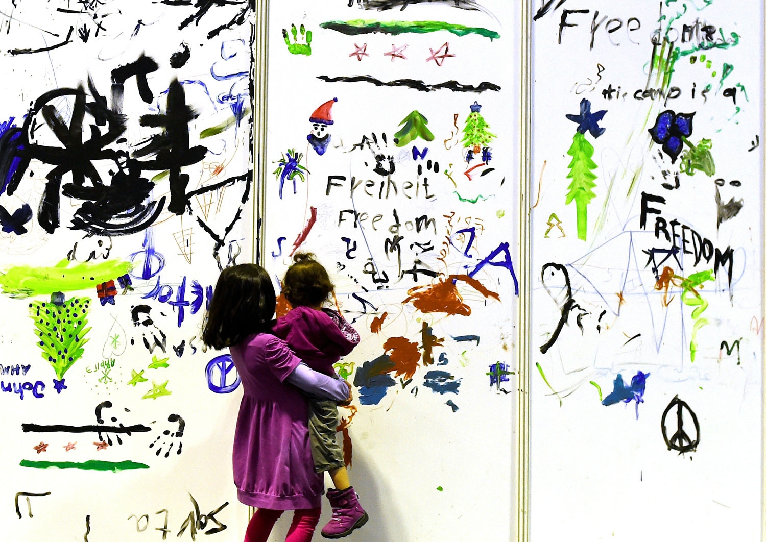 Young refugees pass by a painted wall of a temporary bedroom at a refugee accomodation hosted in a hangar of the former Tempelhof airport in Berlin on December 26, 2015 Young refugees pass by a painted wall of a temporary bedroom at a refugee accomodation hosted in a hangar of the former Tempelhof airport in Berlin on December 26, 2015