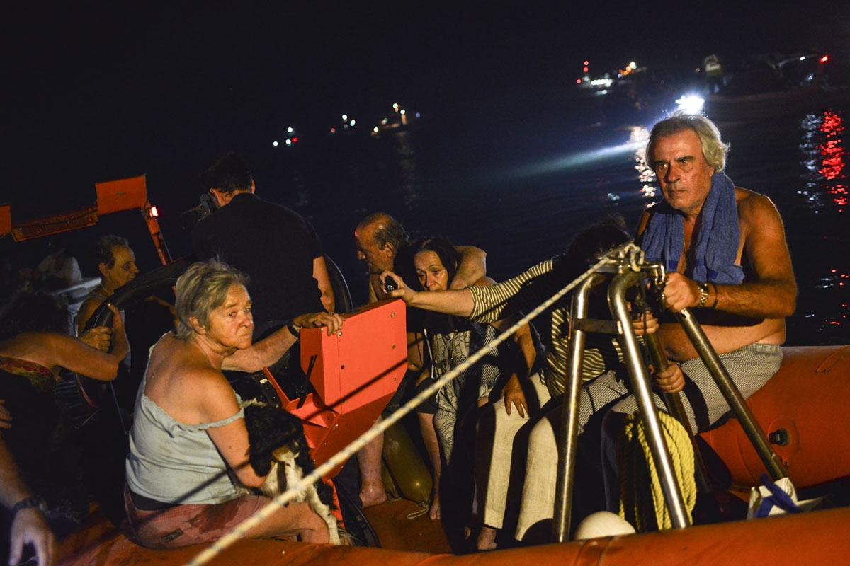 Rescuers and volunteers help local people evacuate the village of Mati during a wildfire near Athens, on July 23, 2018.
