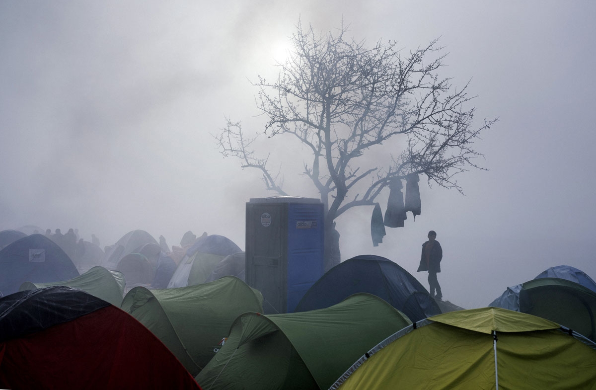A boy stands among tents during a foggy morning at a makeshift camp at the Greek-Macedonian border near the Greek village of Idomeni on March 8, 2016, where thousands of refugees and migrants are trapped by the Balkan border blockade.