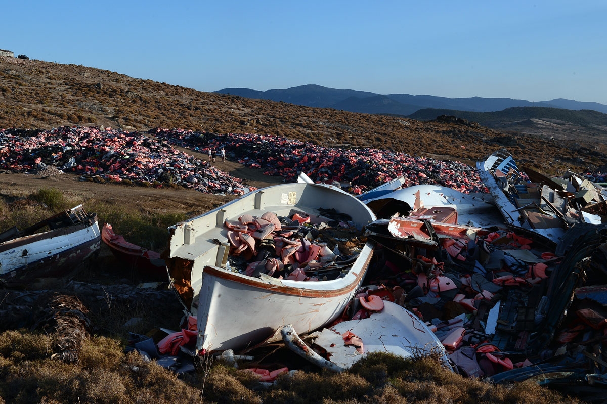 Tourists visit the dump above the village of Molyvos with thousands of lifejackets next to boats collected from the shores, evidence of last year's refugee crisis on July 18, 2016.