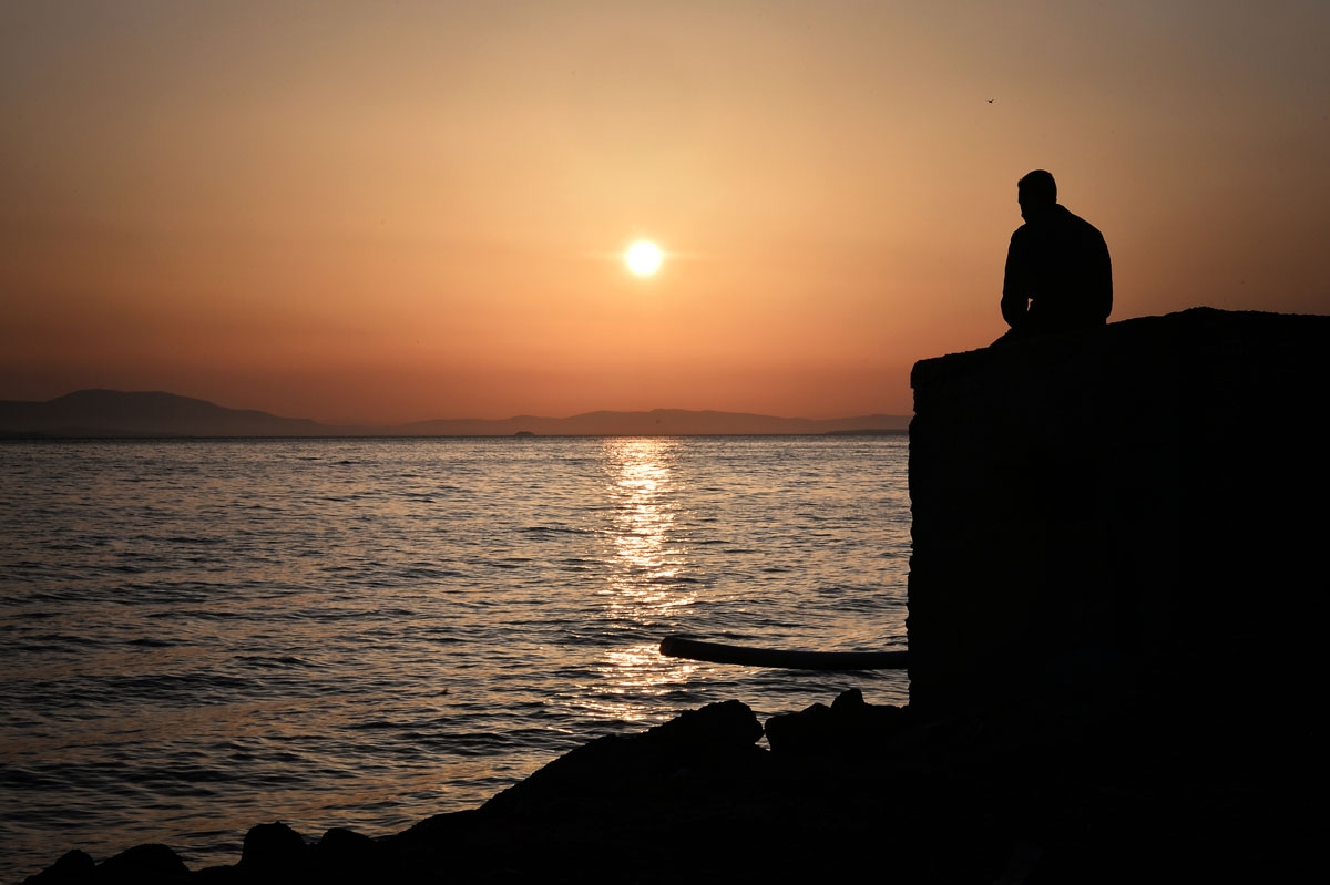A man looks at the sea near the port of Chios, where refugees and migrants who managed to leave the VIAL detention center a few days ago are camping out on April 5, 2016